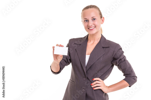 Beautiful young caucasian businesswoman in grey suit and showing blank of white business card isolated on white