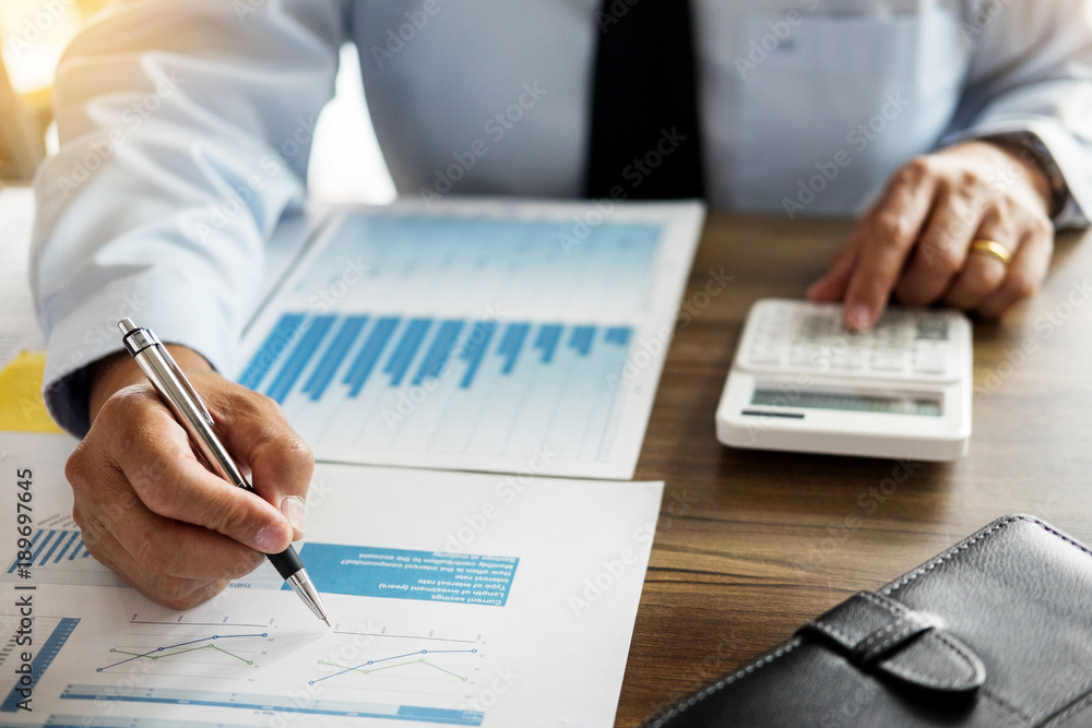 Business man working at office with laptop, tablet and graph data documents on his desk Business man working at office with laptop, tablet and graph data documents on his desk