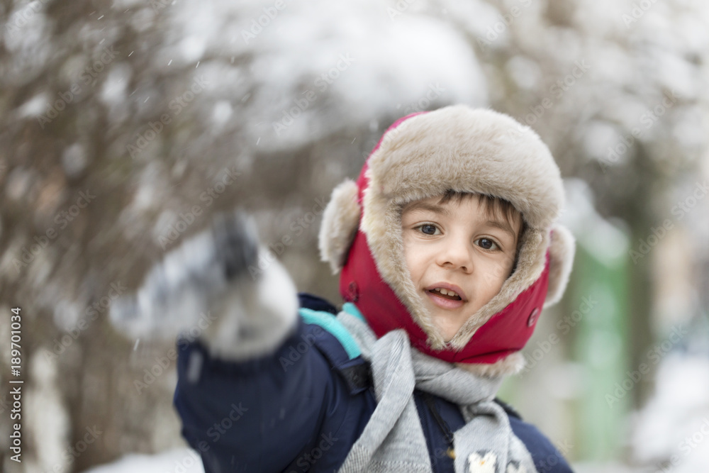 Young boy with fur hat playing with snow Young boy with fur hat playing with snow