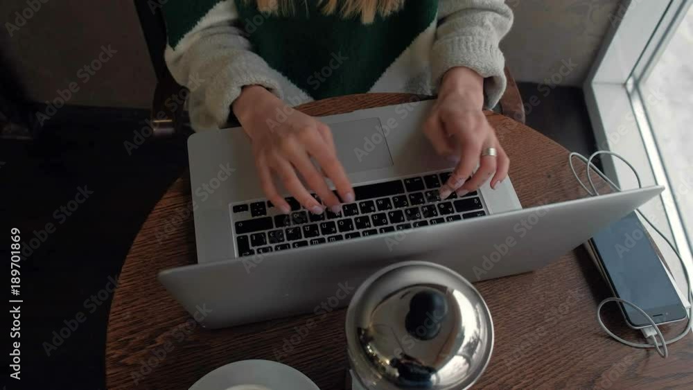 Beautiful girl model sitting at a table in a cafe and working on the computer Beautiful girl model sitting at a table in a cafe and working on the computer