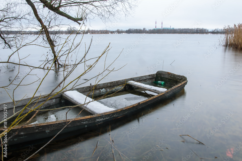 Fototapeta premium Sunken fishing boat on winter lake in Shatura in Moscow Region, Russia