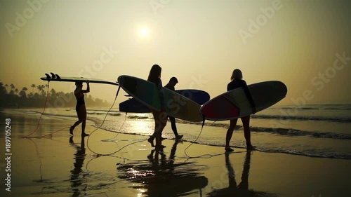 Silhouette surfers with surfboard come into the water sunrise rapid slow motion 