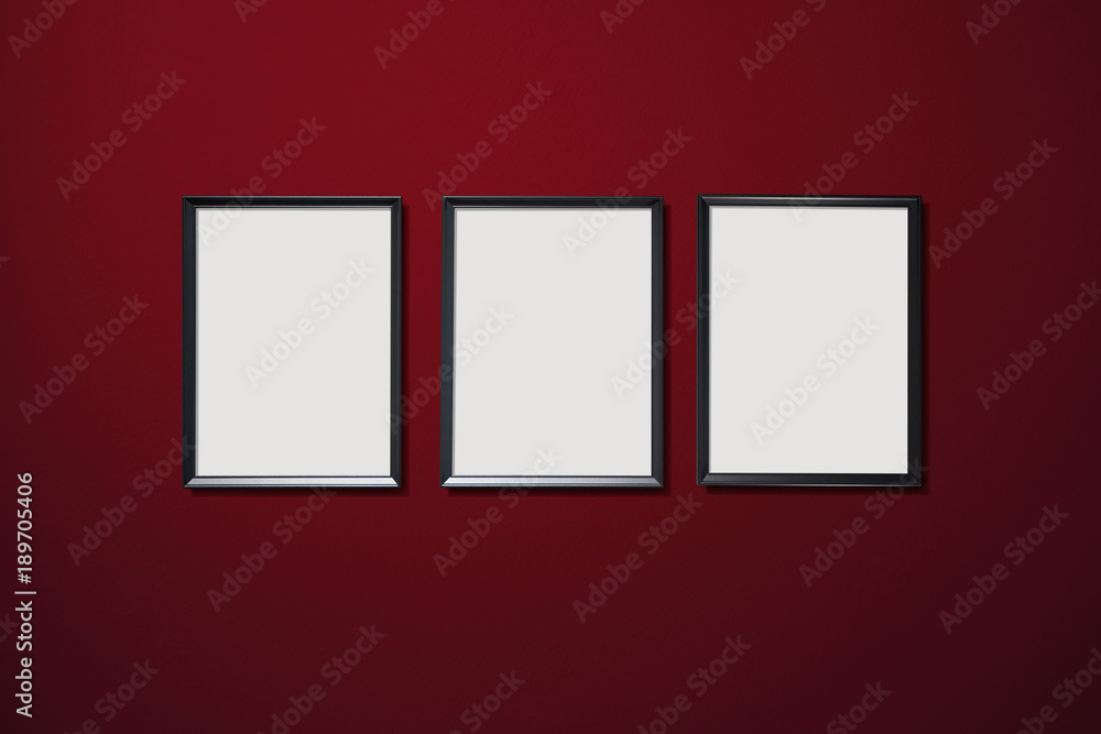 Three empty picture frames hanging on the red color wall . Three empty picture frames hanging on the red color wall .