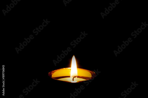 Mourning funeral concept. Single isolated burning yellow candle flame on black. Pet or human condolences.