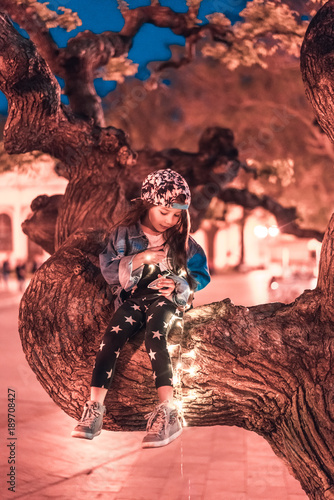 preschool girl sitting on a tree branch