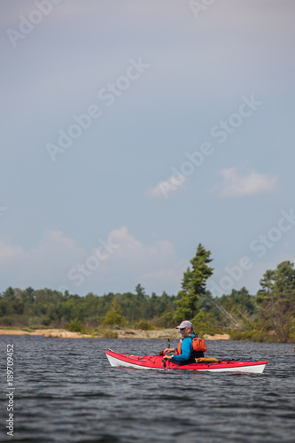 Active senior paddling a sea kayak © Colin