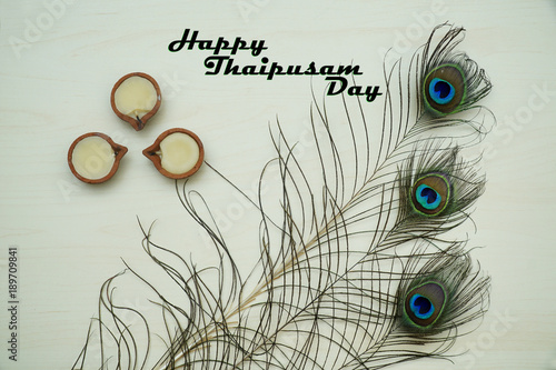 Top or flat lay view of a peacock feathers on a wooden background with a words HAPPY THAIPUSAM DAY. Celebrate by a hindu religions.  A religions conceptual. photo
