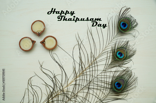 Top or flat lay view of a peacock feathers on a wooden background with a words HAPPY THAIPUSAM DAY. Celebrate by a hindu religions.  A religions conceptual.