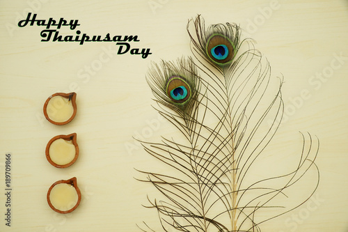 Top or flat lay view of a peacock feathers on a wooden background with a words HAPPY THAIPUSAM DAY. Celebrate by a hindu religions.  A religions conceptual.