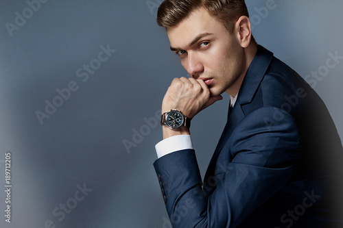 portrait of a man sitting with a suit with a watch, studio