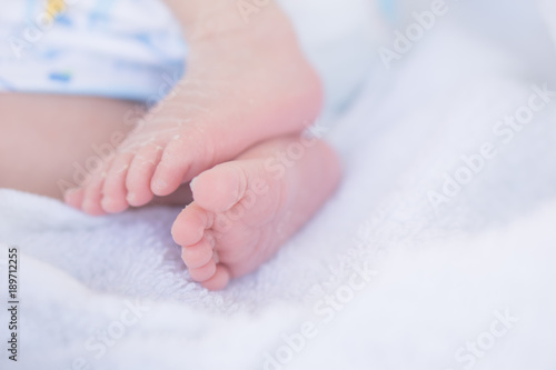 newborn baby feet on white blanket closeup selective focus in soft tone