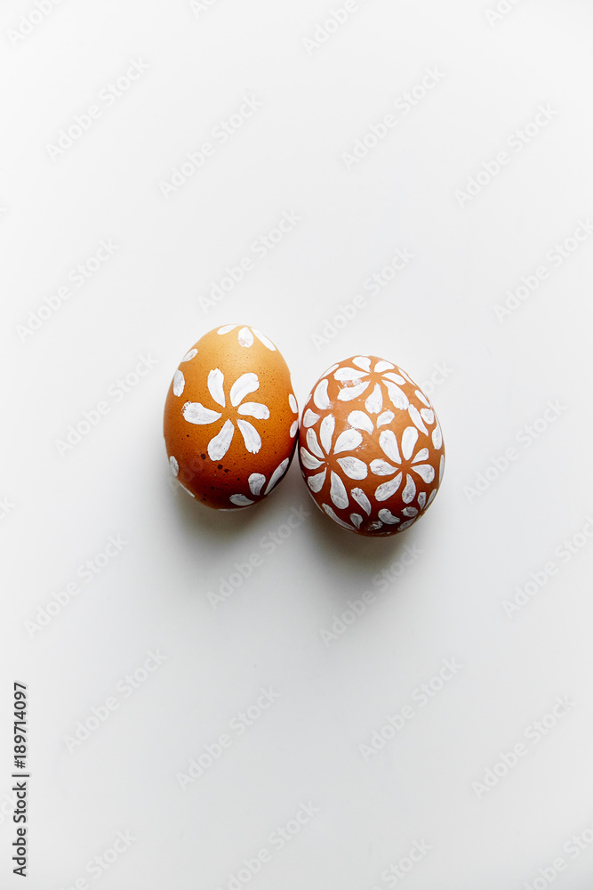 Two eggs painted floral white patterns on Easter holiday. White background, copy space, minimalistic concept