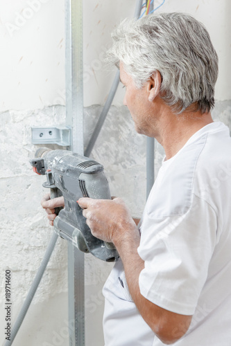 Mason drilling into a wall © auremar