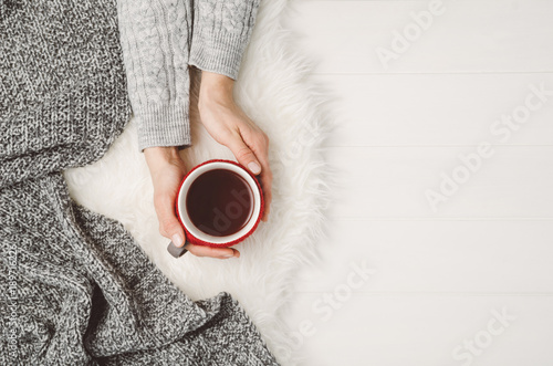 Konstfotografi Female hand holding a cup of tea or coffee on white wooden table