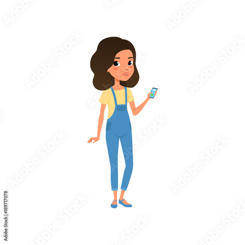 Cute teenager character dressed in yellow t-shirt and blue denim overall. Cartoon girl with smartphone in hand. Stylish casual outfit. Colorful flat vector design