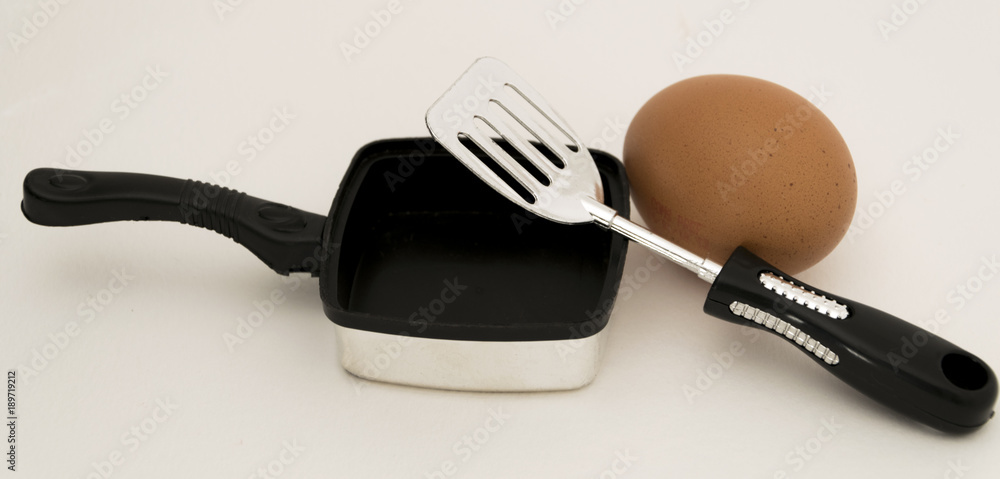 Tamaño problemático. Huevo de gran dimensión para cocinar en una sartén  pequeña y de juguete. Stock Photo
