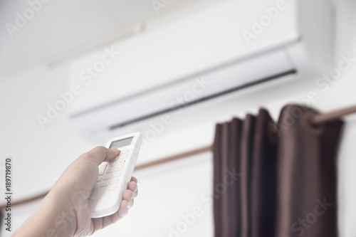A man use remote controller to set air conditioner temperature in the room.Hand holdind control remote switch of home air conditioner