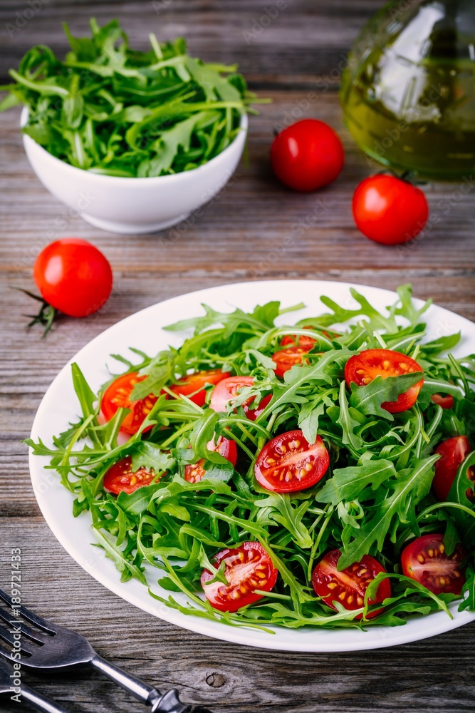 fresh green salad with arugula and red tomatoes on wooden background fresh green salad with arugula and red tomatoes on wooden background