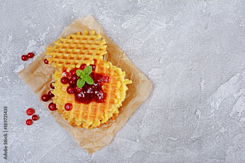 Homemade dessert. Sweet waffles with fresh cranberry, jam and mint on parchment paper Homemade dessert. Sweet waffles with fresh cranberry, jam and mint on parchment paper