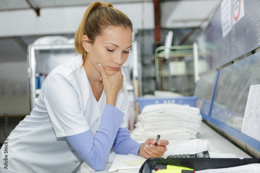 Obraz premium female worker in laundry with calculator doing paperwork