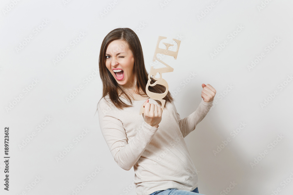 Young happy woman in light casual clothes holding wooden word love, doing winner gesture on white background. Copy space for advertisement. St. Valentine's Day or International Women's Day concept. Young happy woman in light casual clothes holding wooden word love, doing winner gesture on white background. Copy space for advertisement. St. Valentine's Day or International Women's Day concept.