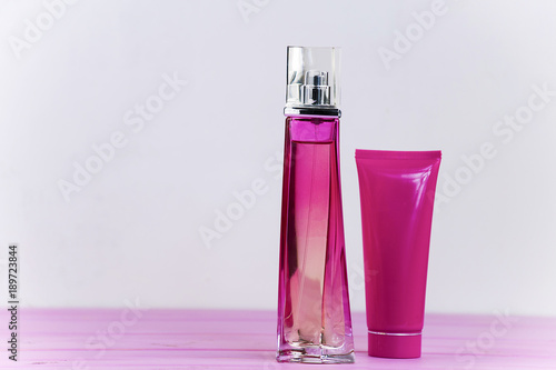 perfume bottle and cream on a pink wooden background