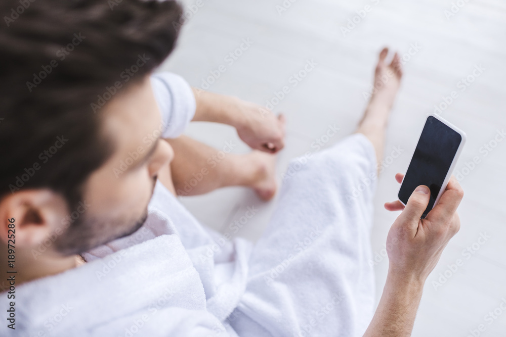 selective focus of bearded man in bathrobe using smartphone with blank screen selective focus of bearded man in bathrobe using smartphone with blank screen