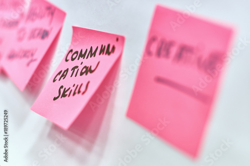 Communication skills written on pink and yellow paper stickers attached to a flip chart on a whiteboard