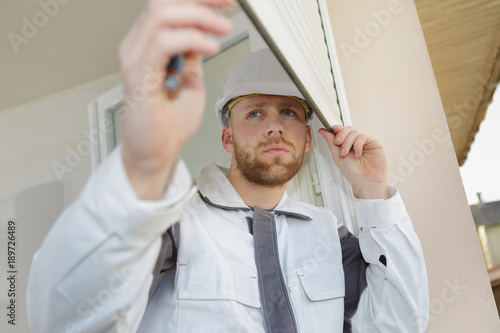 young contractor installing window blinds