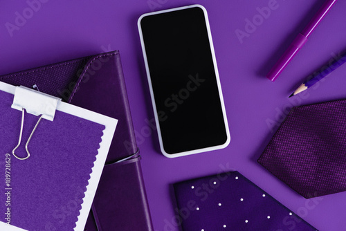 top view of stylish workspace in purple color shades with smartpohone and supplies