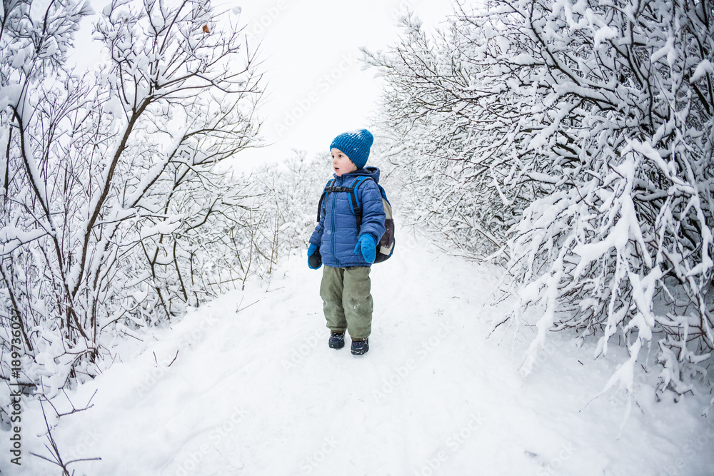 The boy walks through the snow.