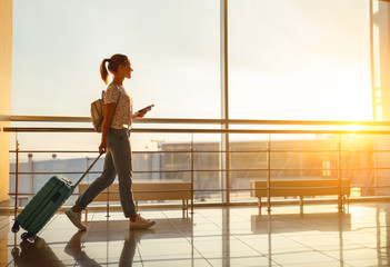 young woman goes  at airport at window with suitcase waiting for plane