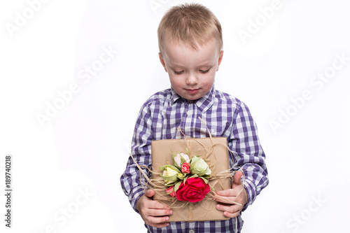 Beautiful caucasian boy holding a box with a gift decorated with flowers. Shooting in studio on isolated white background
