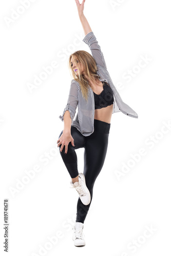 Graceful attractive blonde woman dancing in one leg with hand raised posture. Full body length portrait isolated on white studio background. 