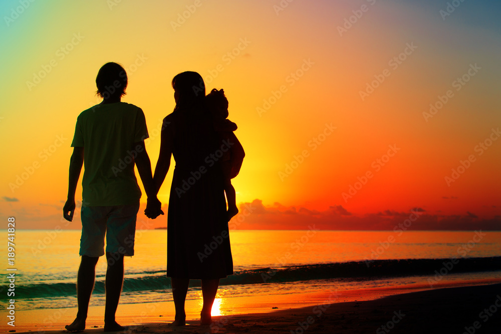 happy romantic couple with small child on tropical beach