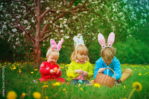 Canvas Print happy kids on easter eggs hunt in spring