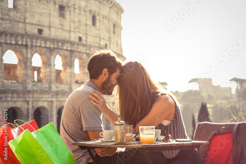 Photography Romantic happy couple young tourists in love kissing cuddling at restaurant in front of colosseum in rome at sunset with lens flare