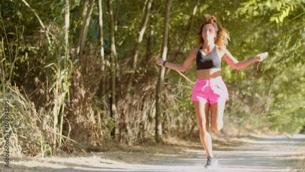 Woman is jumping rope in the park. shot in slow motion Woman is jumping rope in the park. shot in slow motion