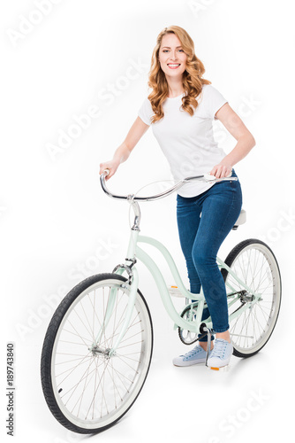 cheerful woman with retro bicycle looking at camera isolated on white