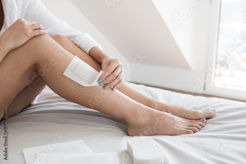 Unrecognisable woman waxing her legs at home.