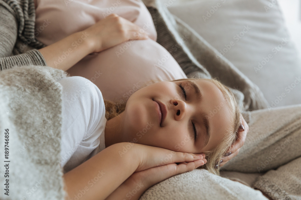 cropped image of daughter sleeping on pregnant mother legs cropped image of daughter sleeping on pregnant mother legs