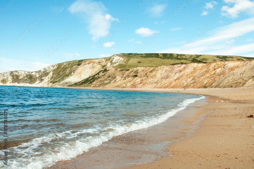 Beautiful summertime beach and ocean waves along Tyneham beach in Dorset, England.