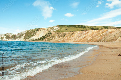 Fototapeta Naklejka Na Ścianę i Meble -  Beautiful summertime beach and ocean waves along Tyneham beach in Dorset, England.