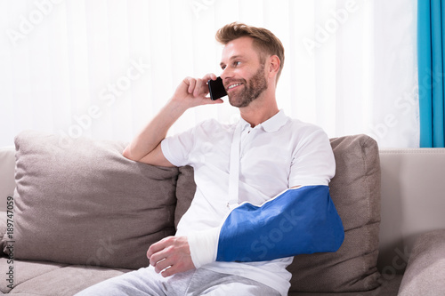 Canvas Print Man With Fractured Hand Talking On Mobile Phone