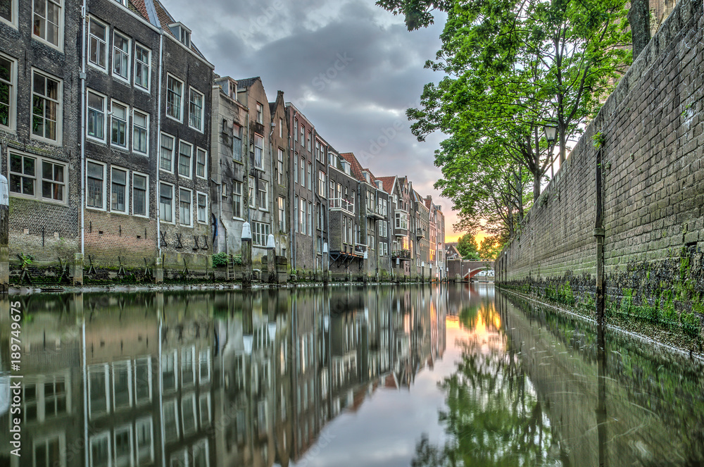 View at sunset of a canal in downtown Dordrecht, The Netherlands with houses built directly on the waterside