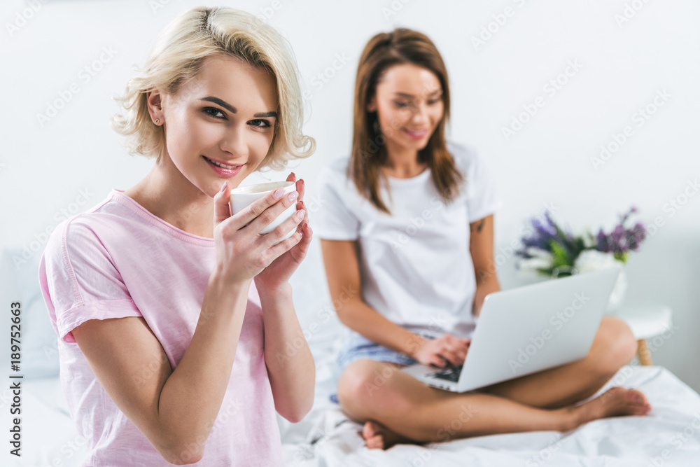 caucasian girls with coffee and laptop on bed caucasian girls with coffee and laptop on bed