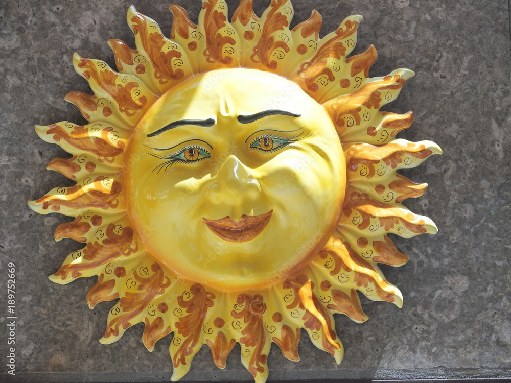Handmade ceramic yellow symbolic sun of SICILY on wall in city center of TAORMINA Handmade ceramic yellow symbolic sun of SICILY on wall in city center of TAORMINA