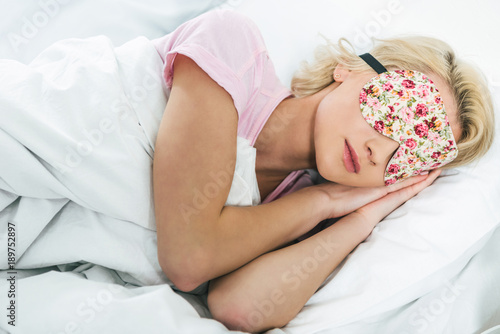 young blonde girl in sleeping mask on bed