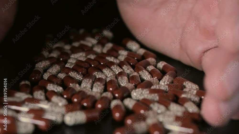 Pills scattered on the table fingers take a pill Pills scattered on the table fingers take a pill