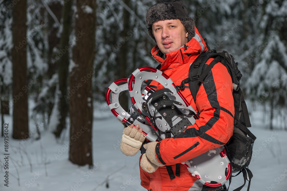 male tourist with snowshoes in the winter forest